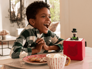 Child playing with Favorite Classics: A Christmas Carol & Tales Tonie