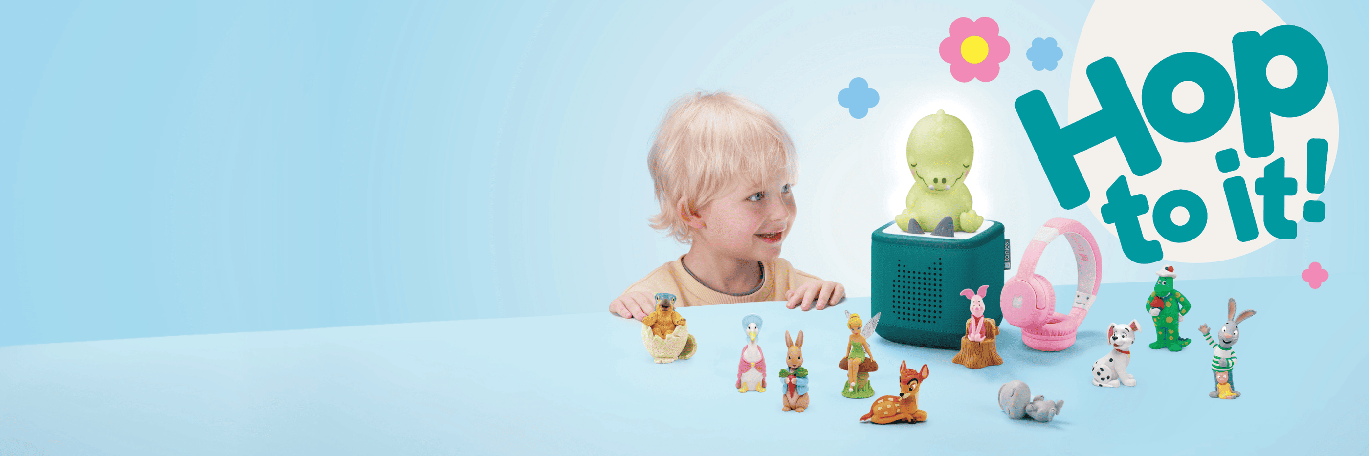 child looking at a teal Toniebox 2 surrounded by Tonies and accessories with text 'Hop to it'
