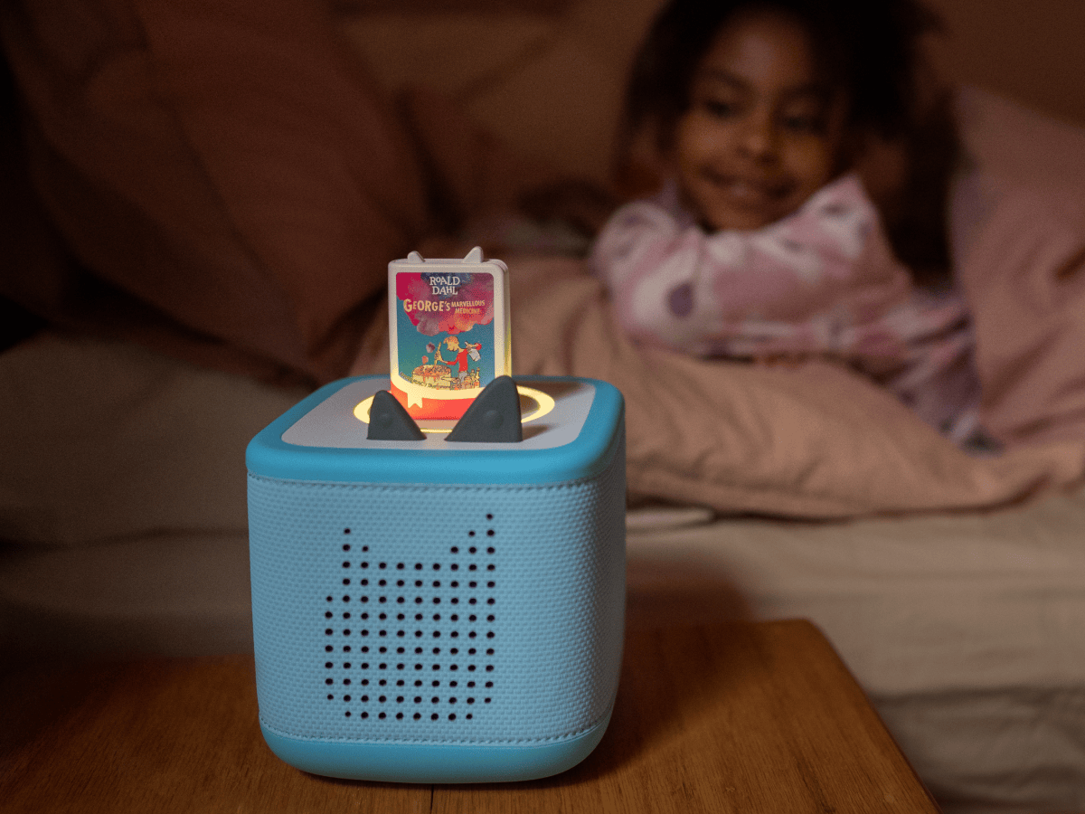 child smiling and listening to Roald Dahl Georges Marvellous Medicine Book Tonie on a blue toniebox 2